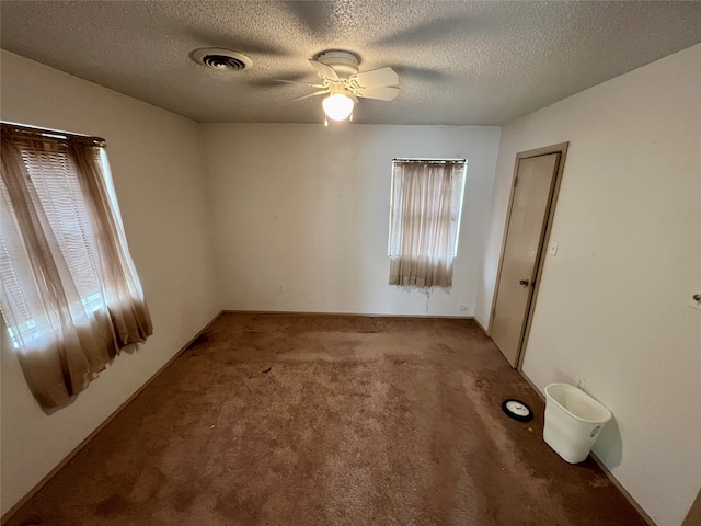 unfurnished room with carpet, ceiling fan, and a textured ceiling