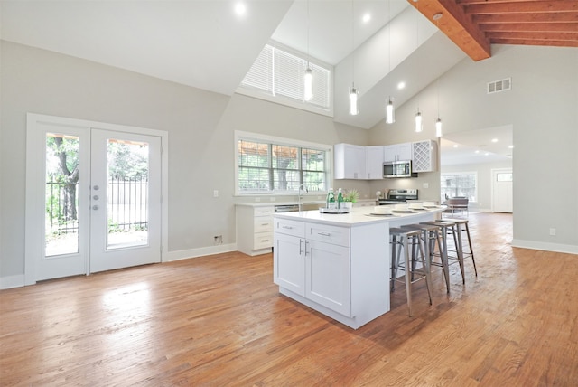 kitchen with beam ceiling, white cabinetry, light hardwood / wood-style flooring, a center island, and high vaulted ceiling