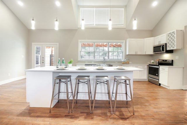 kitchen featuring a center island, light hardwood / wood-style flooring, stainless steel appliances, and high vaulted ceiling