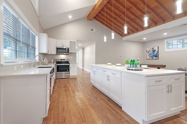 kitchen featuring appliances with stainless steel finishes, beamed ceiling, wooden ceiling, and white cabinets