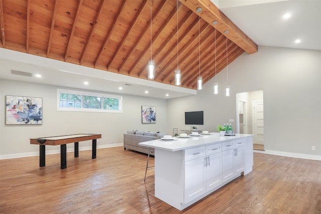 kitchen featuring white cabinetry, pendant lighting, high vaulted ceiling, beamed ceiling, and a center island