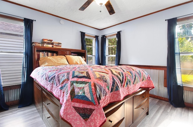 bedroom with a textured ceiling, light hardwood / wood-style flooring, ornamental molding, and ceiling fan