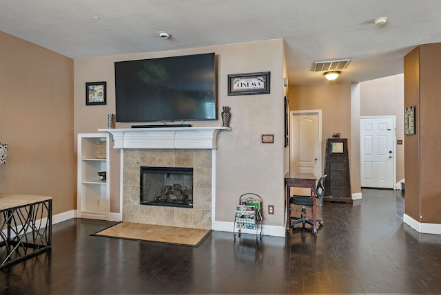 living room featuring hardwood / wood-style flooring, a tiled fireplace, and a textured ceiling