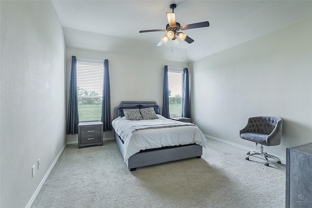 bedroom with ceiling fan, light colored carpet, and multiple windows