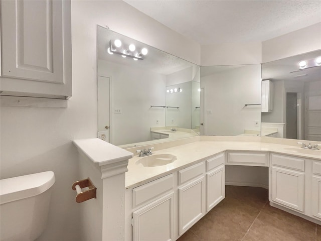 bathroom featuring vanity, tile patterned floors, a textured ceiling, and toilet