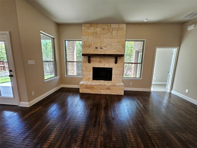 unfurnished living room featuring a fireplace, dark wood-type flooring, and plenty of natural light