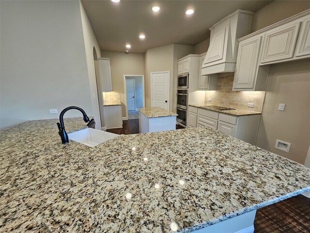 kitchen featuring white cabinets, light stone countertops, sink, and a center island