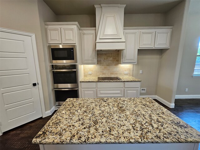 kitchen featuring appliances with stainless steel finishes, light stone countertops, dark wood-type flooring, and custom range hood