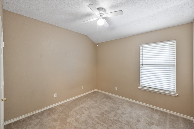 empty room with carpet floors, a textured ceiling, ceiling fan, and vaulted ceiling