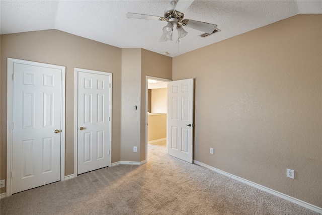 unfurnished bedroom with lofted ceiling, a textured ceiling, carpet floors, and ceiling fan