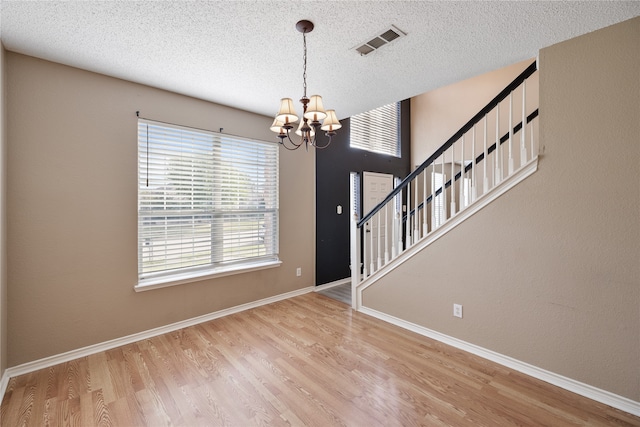 entrance foyer featuring a textured ceiling, light hardwood / wood-style flooring, and an inviting chandelier