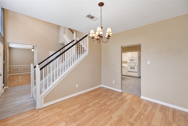 interior space featuring light hardwood / wood-style floors, a notable chandelier, and a textured ceiling