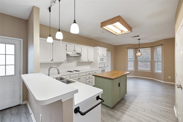 kitchen featuring white appliances, white cabinets, sink, decorative backsplash, and a center island