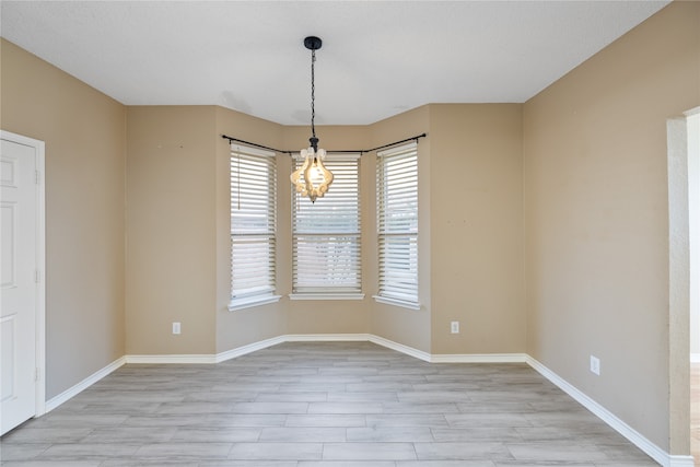 empty room featuring light hardwood / wood-style floors and a notable chandelier