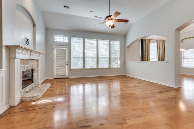 unfurnished living room featuring light hardwood / wood-style flooring, a fireplace, lofted ceiling, and a healthy amount of sunlight