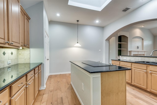 kitchen with pendant lighting, sink, backsplash, and a center island