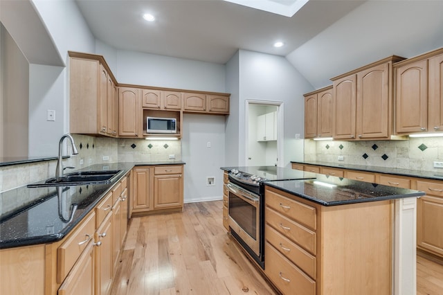 kitchen with sink, a center island, light hardwood / wood-style flooring, dark stone countertops, and stainless steel appliances