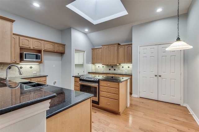 kitchen with hanging light fixtures, stainless steel appliances, decorative backsplash, dark stone counters, and light wood-type flooring