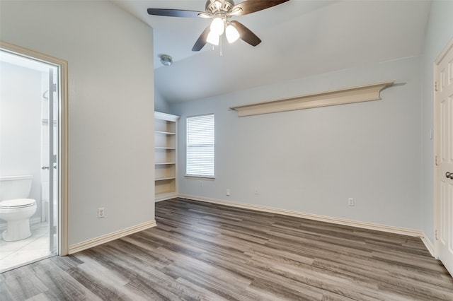 unfurnished bedroom featuring ceiling fan, ensuite bath, lofted ceiling, and hardwood / wood-style flooring