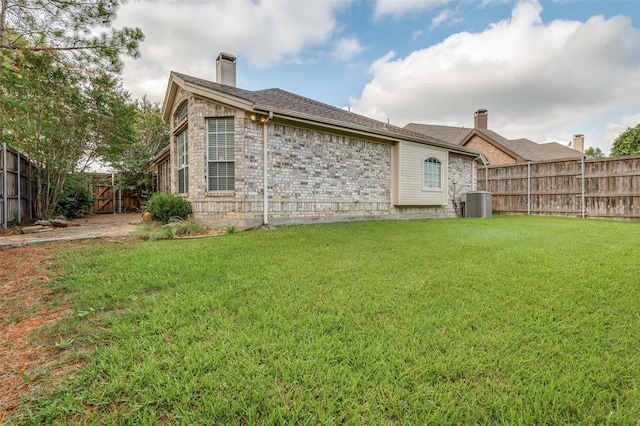 rear view of house with central air condition unit and a lawn