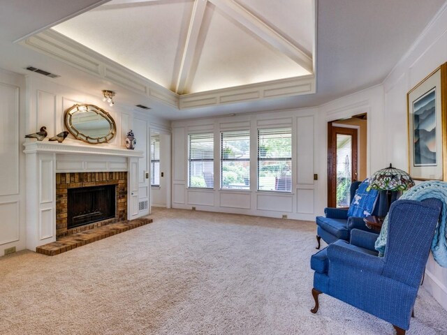 carpeted living room featuring a fireplace, vaulted ceiling, crown molding, and a raised ceiling