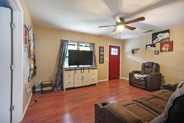 living room with dark wood-type flooring, a textured ceiling, and ceiling fan