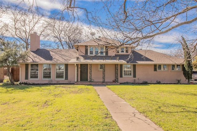 traditional-style home with stucco siding, a shingled roof, a chimney, and a front yard