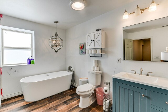 bathroom with hardwood / wood-style floors, a washtub, toilet, vanity, and a chandelier