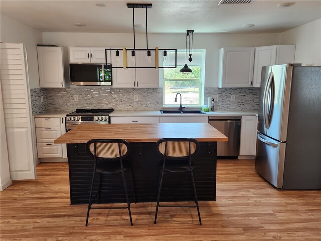 kitchen featuring light wood-type flooring, white cabinets, a center island, stainless steel appliances, and sink