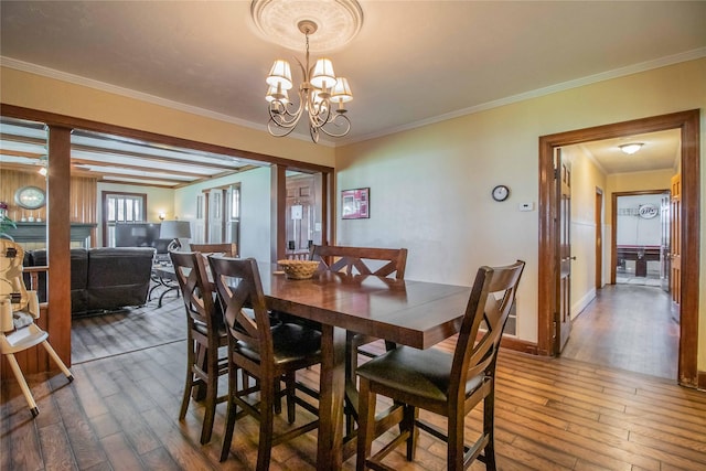 dining room with ornamental molding, wood finished floors, and an inviting chandelier