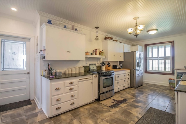 kitchen with dark countertops, appliances with stainless steel finishes, white cabinets, and a chandelier