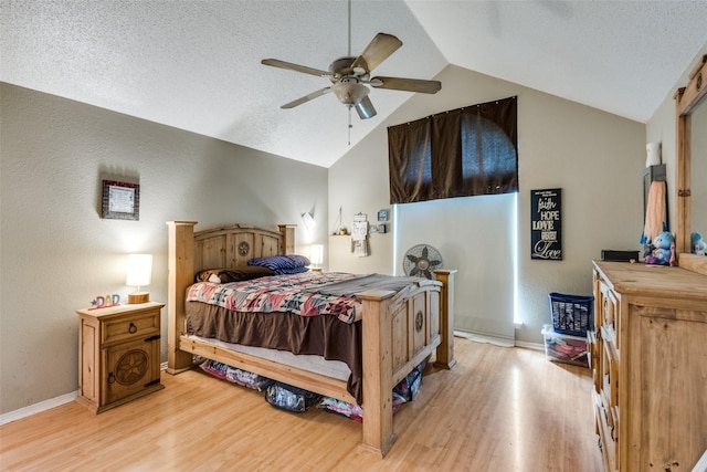 bedroom with ceiling fan, vaulted ceiling, light hardwood / wood-style floors, and a textured ceiling