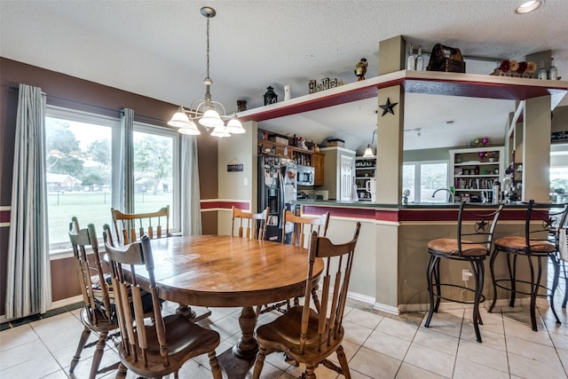 tiled dining space featuring a chandelier, a wealth of natural light, and a textured ceiling