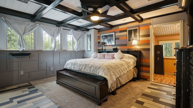 bedroom featuring hardwood / wood-style flooring, beamed ceiling, coffered ceiling, and ceiling fan