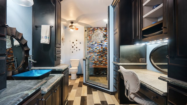 bathroom with hardwood / wood-style floors, vanity, ceiling fan, and toilet