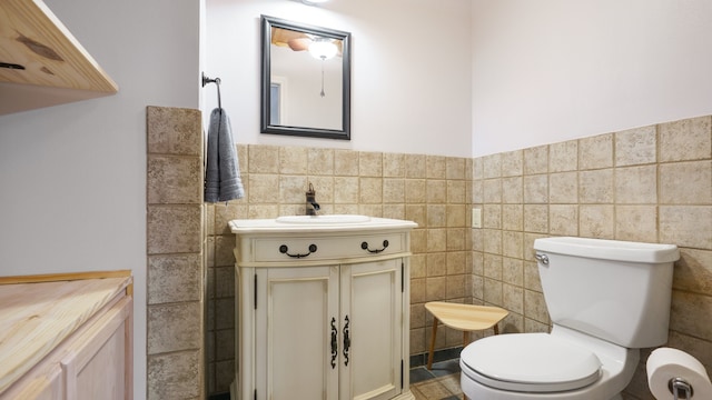 bathroom featuring toilet, vanity, tile patterned flooring, and tile walls