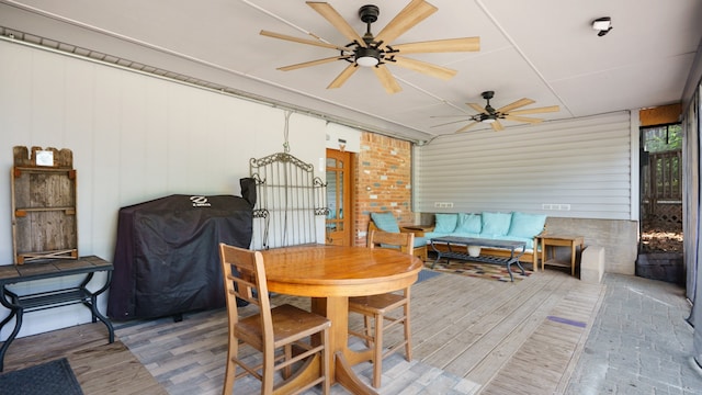 dining area featuring brick wall, ceiling fan, and hardwood / wood-style floors