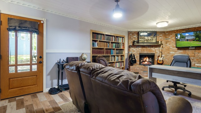 living room featuring a fireplace, light hardwood / wood-style floors, brick wall, and ornamental molding