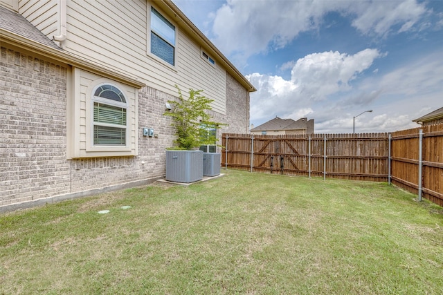 view of yard with central AC and fence