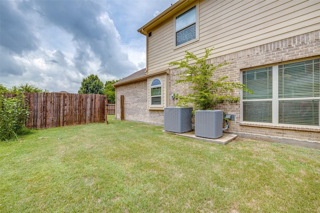 view of yard featuring central AC and fence