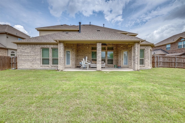 rear view of house with a yard, a patio, brick siding, and a fenced backyard