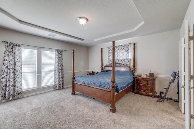 bedroom with baseboards, visible vents, a tray ceiling, a textured ceiling, and carpet floors