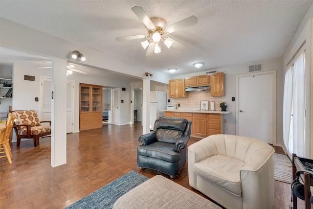 living room with ceiling fan, dark parquet flooring, and a textured ceiling