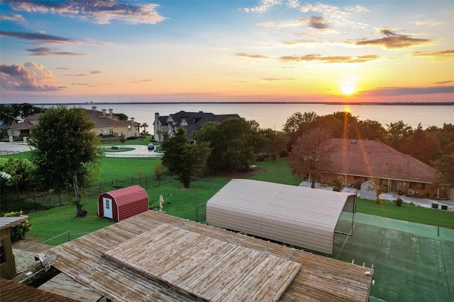 deck at dusk with a water view and a storage unit