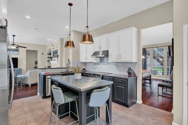 kitchen with hanging light fixtures, kitchen peninsula, backsplash, white cabinets, and light hardwood / wood-style floors