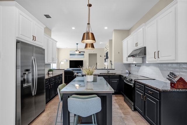 kitchen featuring decorative backsplash, ceiling fan, a kitchen island, pendant lighting, and stainless steel appliances