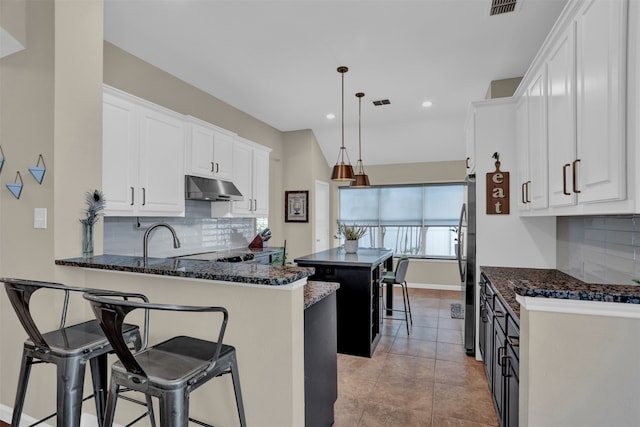 kitchen with a center island, a kitchen breakfast bar, decorative light fixtures, white cabinets, and decorative backsplash