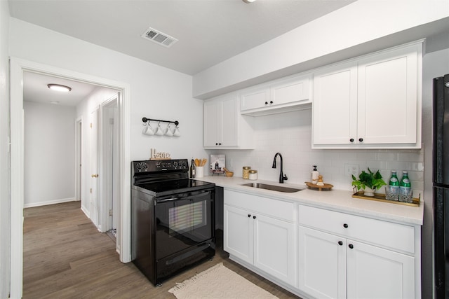 kitchen with white cabinets, sink, light hardwood / wood-style flooring, backsplash, and black range with electric cooktop