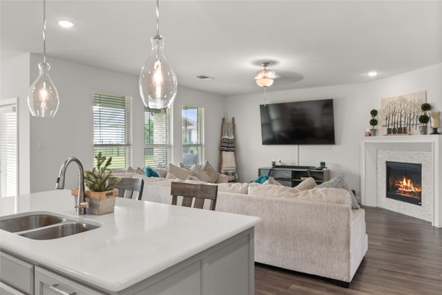 kitchen with sink, a kitchen island with sink, dark hardwood / wood-style floors, and decorative light fixtures