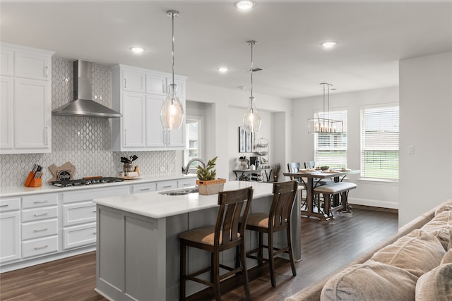 kitchen featuring an island with sink, stainless steel gas cooktop, sink, and wall chimney exhaust hood